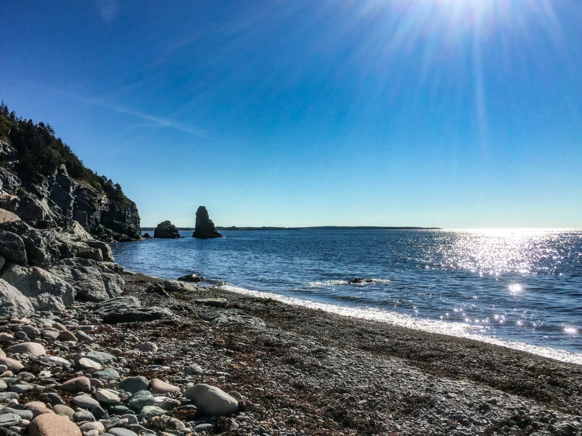 Bucht mit Kiesstrand mit Blick auf das Wasser im Gegenlicht