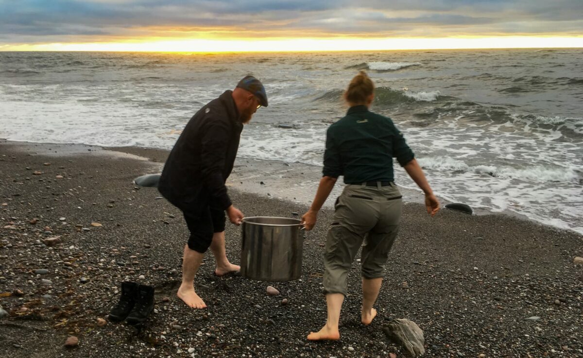 Zwei Personen gießen Kochwasser zurück ins Meer